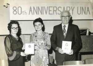 Two women and one man receiving plaques at the 80th Anniversary celebration of The UNA
